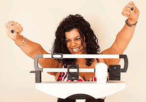 Woman celebrating while standing on a scale.