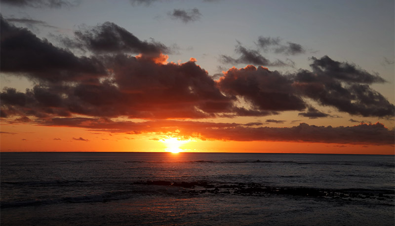 sunset over water ocean clouds